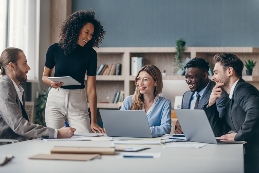 Diverse team collaborating around a conference table with woman presenting